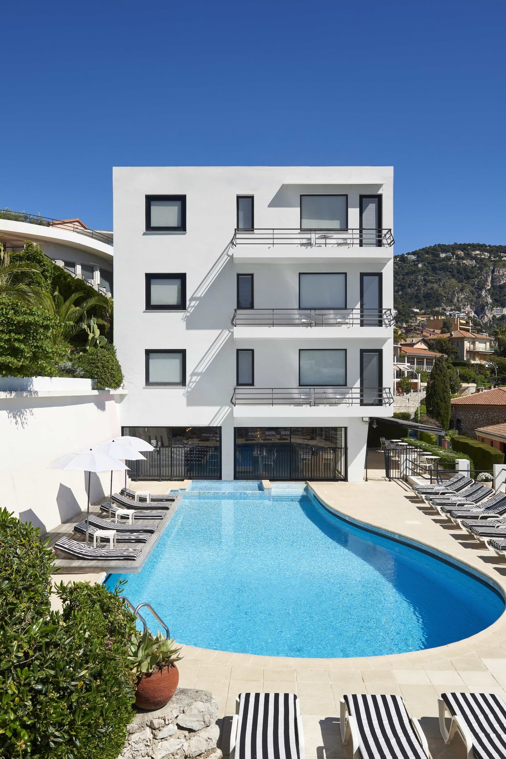 Vu de face de l'hotel le versailles avec piscine et transat