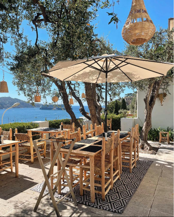 Terrasse ombragé sous les olivier de l'hôtel le versailles avec vu sur la rade de ville franche sur mer