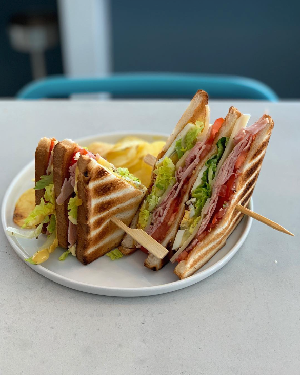 Sandwich triangle fais maison posé dans une jolie assiette blanche sur le bar du pool house
